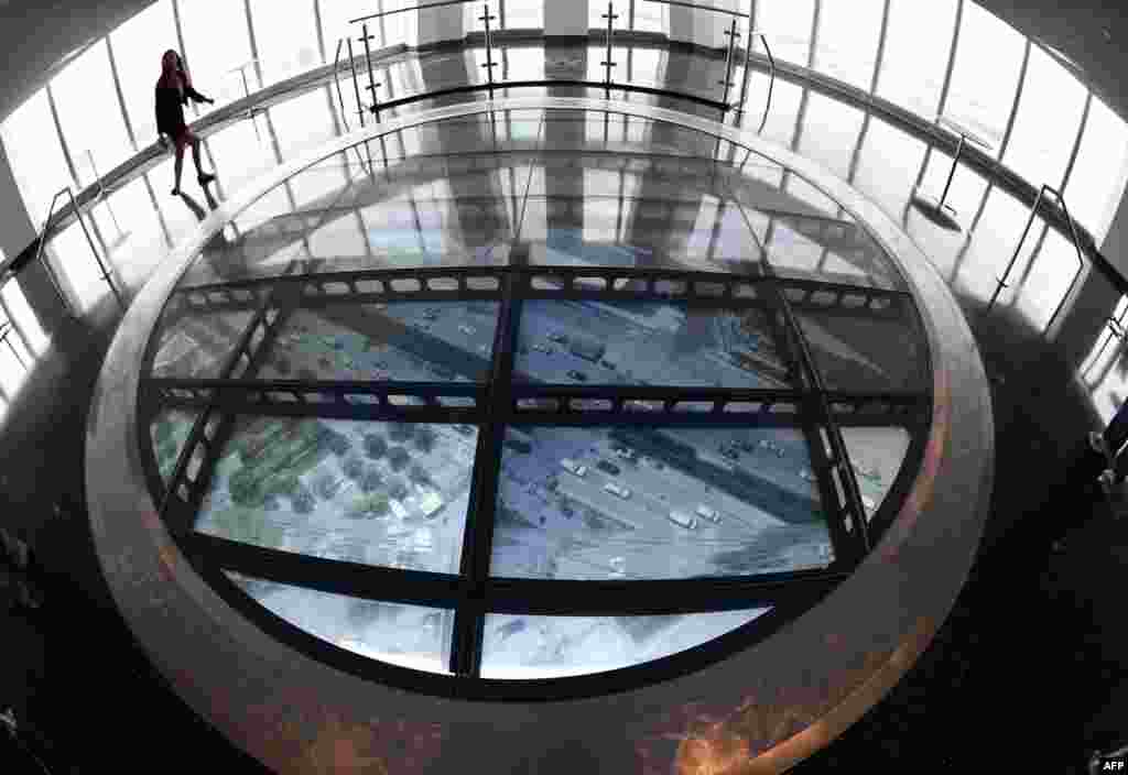 A member of the media stands on the Sky Portal, a 14-foot-wide disc that delivers high-def footage from the street below at the One World Observatory in New York.