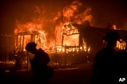 FILE - Flames from a wildfire consume a residence near Oroville, California, July 9, 2017.