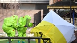 In this file photo taken on March 8, 2018 members of the emergency services in green biohazard encapsulated suits re-affix the tent over the bench where Russian spy Sergei Skripal and his daughter Yulia were found in critical condition