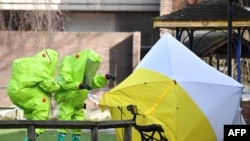 FILE - Officials in protective suits reposition the forensic tent over the bench where Russian spy Sergei Skripal and his daughter, Yulia, were found in critical condition on March 4 in Salisbury, southern England, March 8, 2018. 