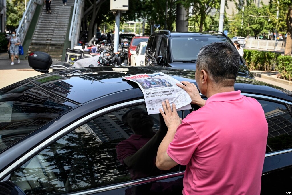 一名男子在北京街头阅读中共官媒环球时报对塔利班占领喀布尔的报道。（2021年8月17日）(photo:VOA)