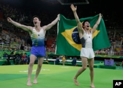 Brazil's Arthur Mariano, right, and compatriot Diego Hypolito celebrate with their national flag after winning bronze and silver respectively for the floor during the artistic gymnastics men's apparatus final at the 2016 Summer Olympics in Rio de Janeiro,