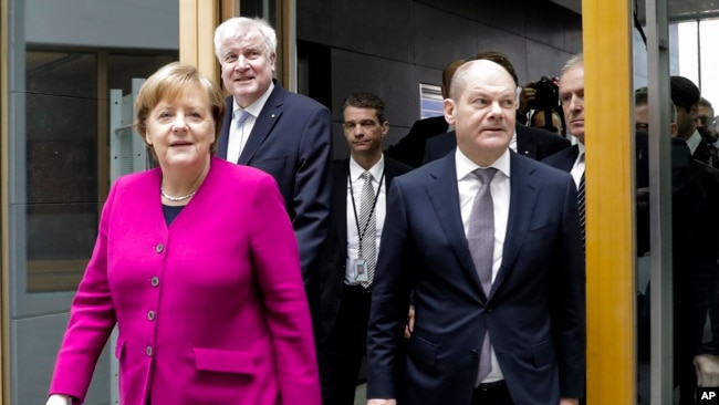 German Chancellor and Christian Democratic Union, CDU, party chairwoman Angela Merkel, left, Christian Social Union, CSU, party chairman Horst Seehofer, second from left, and Social Democratic Party, SPD temporary party leader Olaf Scholz, right, arrive for a news conference, in Berlin, Germany, Monday, March 12, 2018.