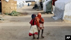 Ami and Ashbu, both three-years-old, walk arm in arm in the Zafaye refugee camp, some 15 kms (10 miles) from downtown N'djamena, Chad, March 11, 2015
