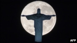 The silhouette of the statue of Christ the Redeemer atop Corcovado hill stands out against the full moon in Rio de Janeiro, Brazil, on July 19, 2016.