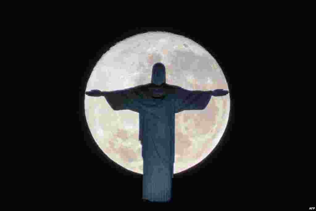 The silhouette of the statue of Christ the Redeemer atop Corcovado hill stands out against the full moon in Rio de Janeiro, Brazil.