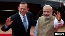 Australia's Prime Minister Tony Abbott and his Indian counterpart Narendra Modi (R) wave towards the media during Abbott's ceremonial reception at the forecourt of India's presidential palace Rashtrapati Bhavan in New Delhi, Sept. 5, 2014. 