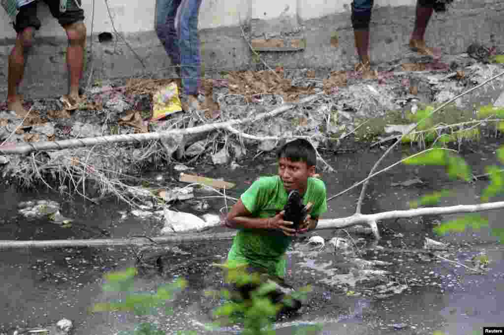 A protester takes shelter in a drain after police charged with batons during a demonstration in Savar, outside Dhaka, Bangladesh, to demand capital punishment for those responsible for the collapse of the building.