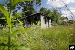 FILE - An abandoned house with an overgrown lot is seen in Brightmoor, a neighborhood on Detroit’s northwest side, July 19, 2013. Brightmoor is one of the city’s more blighted neighborhoods.