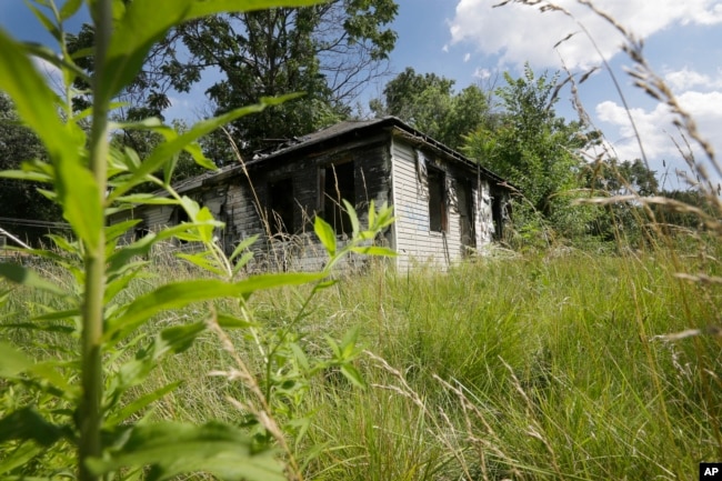 FILE - An abandoned house with an overgrown lot is seen in Brightmoor, a neighborhood on Detroit’s northwest side, July 19, 2013. Brightmoor is one of the city’s more blighted neighborhoods.