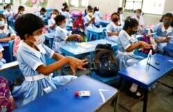 Students apply hand sanitiser in a class at the Viqarunnisa Noon School & College after the government has withdrawn restrictions on educational institutions following a decrease in the number of cases of COVID-19 in Dhaka, Bangladesh, Sept. 12, 2021.