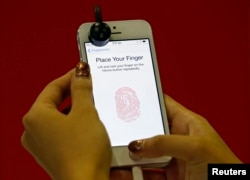 A promoter demonstrates the fingerprint scanner feature of the newly launched Apple iPhone 5S in Singapore, Sept. 20, 2013.