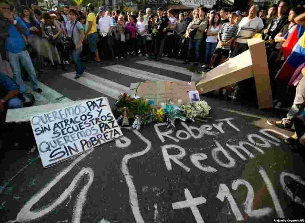 Estudantes assistem a uma vigília para lamentar a morte de dois estudantes durante confrontos violentos em Caracas, Venezuela, na quinta-feira, 13 de fevereiro, 2014. Durante a vigília os estudantes exigiram justiça para, Bassil Da Costa e Robert Redman. O cartaz na esquerda diz: "Nós queremos a paz, sem assaltos, seqüestros. Queremos paz sem pobreza."