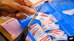 FILE - An elections clerk cuts from a strip of "I Voted" stickers at a polling place in Oklahoma City, June 28, 2016. Officials in Oklahoma, Texas and Louisiana say they've denied a request by Russian officials to be present at polling stations during next month's election.