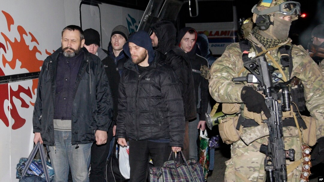 Seorang prajurit Ukraina berjalan di dekat para separatis pro-Rusia dalam pertukaran tawanan perang di dekat Donetsk Ukraina timur, 26/12/2014.