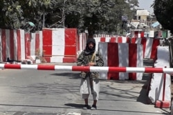 A Taliban fighter stands guard at the entrance of the police headquarters in Ghazni on August 12, 2021, as Taliban move closer to Afghan capital after taking Ghazni city.