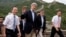 U.S. Secretary of State John Kerry, center, and U.S. Treasury Secretary Jacob Lew, second from right, wave to journalists as they visit to Badaling Great Wall of China in Beijing, China, July 8, 2014. 