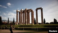 FILE - A tourist makes her way at the archaeological site of the Temple of the Olympian Zeus in Athens, Greece, Nov. 18, 2014. 