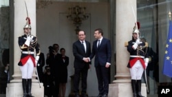 ປະທານາທິບໍດີ ທີ່ພົ້ນຈາກຕຳແໜ່ງ ທ່ານ Francois Hollande, ກາງຊ້າຍ, ຕ້ອນຮັບປະທານາທິບໍດີ ຝຣັ່ງ
ຄົນໃໝ່ ທ່ານ Emmanuel Macron ໃນເວລາທີ່ທ່ານ
ເດີນທາງຮອດພິທີເຂົ້າຮັບຕຳແໜ່ງຂອງທ່ານຢູ່ທຳນຽບ ເອລີເຊ ໃນນະຄອນຫຼວງ ປາຣີ. 14 ພຶດສະພາ, 2017. 