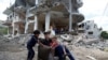 Palestinians sit on chair amid the rubble of a building which was damaged in Israeli air strikes during the Israel-Hamas fighting in Gaza May 23, 2021.