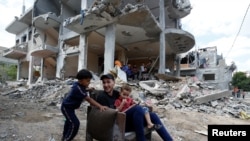 Palestinians sit on chair amid the rubble of a building which was damaged in Israeli air strikes during the Israel-Hamas fighting in Gaza May 23, 2021.