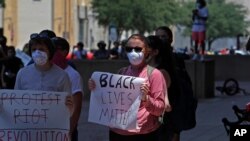 Manifestantes en Dallas, Texas, sostienen carteles frente al municipio de la ciudad el sábado 30 de mayo de 2020, en protestas por la muerte del afroestadounidense George Floyd en custodia de la policía en Minneapolis.