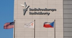 FILE - Signage is seen on the headquarters building of Radio Free Europe/Radio Liberty (RFE/RL), with the United States, RFE/RL and the Czech Republic's flags fluttering in the foreground, in Prague. (Jan Rambousek - RFE/RL)