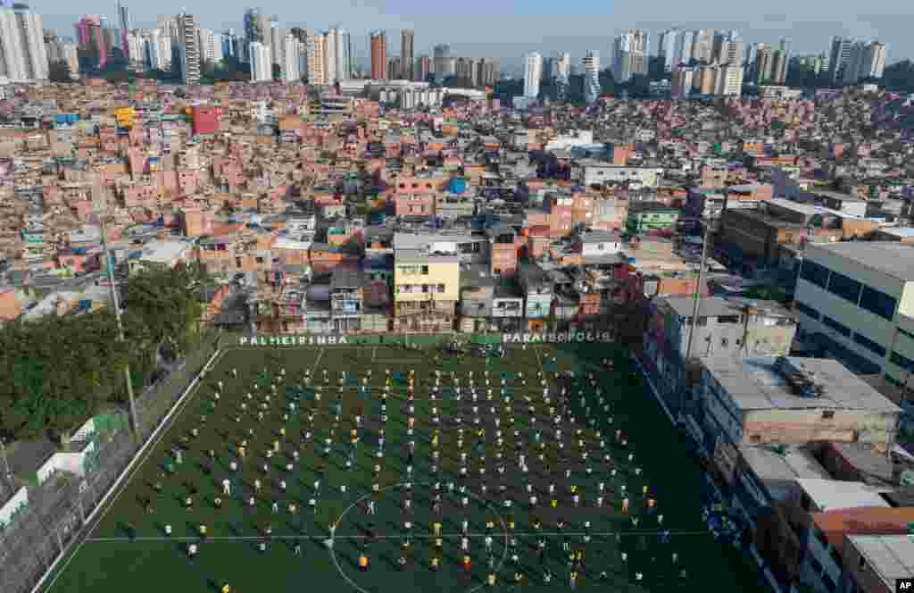 Residents of the Paraisopolis shantytown neighborhood attend a ceremony on a soccer field in Sao Paulo, Brazil. With more than 100,000 residents living in close proximity, Paraisopolis is one of the areas of Sao Paulo most affected by the coronavirus.