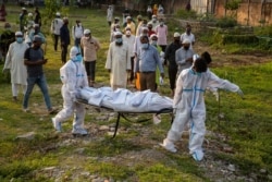 Municipal workers prepare to bury the body of a person who died of COVID-19, in Gauhati, India, Apr. 25, 2021.