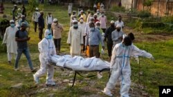 Municipal workers prepare to bury the body of a person who died of COVID-19, in Gauhati, India, April 25, 2021.