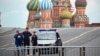 FILE - Police officers stand next to their car in an empty Red Square with St. Basil's Cathedral in the background, in Moscow, Russia, June 28, 2023.