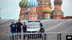 FILE - Police officers stand next to their car in an empty Red Square with St. Basil's Cathedral in the background, in Moscow, Russia, June 28, 2023.