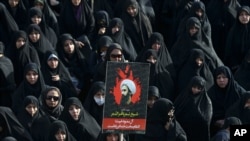 In this Jan. 4, 2016 file photo, an Iranian woman holds up a poster showing Sheikh Nimr al-Nimr, a prominent opposition Saudi Shiite cleric who was executed by Saudi Arabia, in Tehran, Iran. 