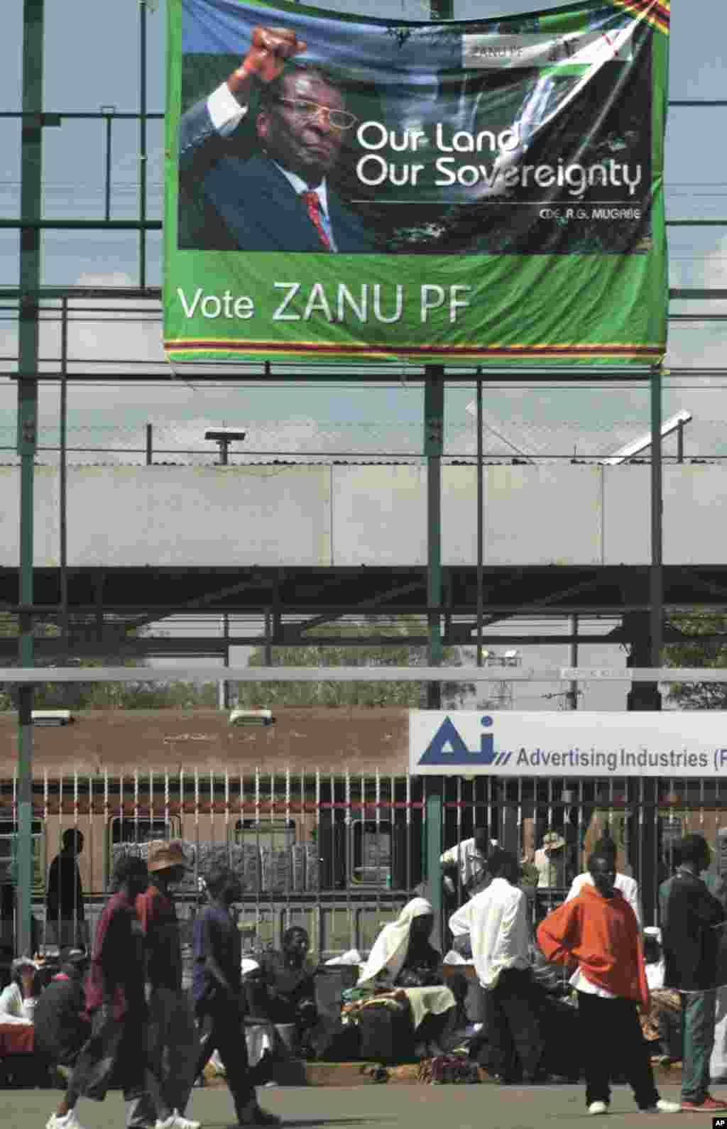 Pedestrians pass beneath an election banner with a portrait of Zimbabwe&#39;s President Robert Mugabe in Harare Tuesday April 15, 2008. Additional police and soldiers were deployed across Zimbabwe&#39;s capital Tuesday as the country&#39;s opposition urged Zimbabweans to join in a nationwide strike to press for the released of long-delayed presidential results.