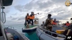 FILE - In this image provided by Armed Forces of the Philippines, a Chinese Coast Guard holds an axe as they approach Philippine troops on a resupply mission in the Second Thomas Shoal at the disputed South China Sea on June 17, 2024. 