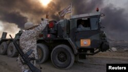 Iraqi soldiers are seen in Qayyara, Iraq, Oct. 22, 2016. The fumes in the background are from oil wells that were set ablaze by Islamic State militants.