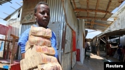 A dealer carries bundles of the Somalian currency at an open air currency exchange within the Hamarweyne open air market in Mogadishu, Somalia, Feb. 5, 2020. The World Bank and IMF have announced that Somalia is eligible for debt relief.