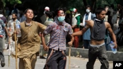 Pakistani protesters help escort their injured colleague to an ambulance during a protest near prime minister's home in Islamabad, Sunday, Aug. 31, 2014.