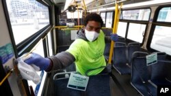 Robert Day works on disinfecting surfaces on a bus in Detroit, April 8, 2020, where buses will have surgical masks available to riders, a new precaution the city is taking from the new coronavirus COVID-19.