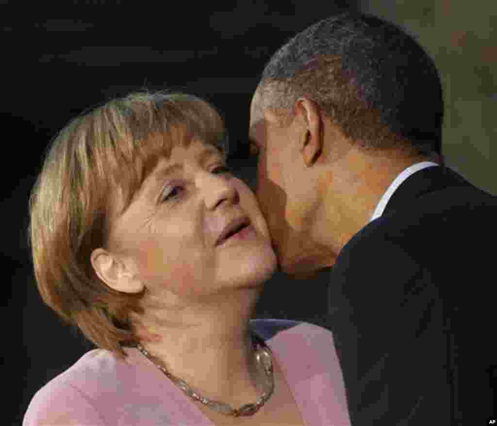 President Barack Obama kisses German Chancellor Angela Merkel on the cheek on arrival for the G8 Summit Friday, May 18, 2012 at Camp David, Md. (AP Photo/Charles Dharapak)