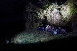 In this photo taken Saturday, Nov. 9, 2019, Bosnian border police officers guard migrants after making the illegal crossing from Serbia by the Drina river, the natural border between Bosnia and Serbia, near eastern Bosnian town of Zvornik, Bosnia…