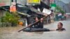 Seorang perempuan menggunakan rakit dari ban mengarungi banjir setelah hujan deras menyebabkan banjir di Bekasi, Jawa Barat, 1 Januari 2020. (Foto: AFP)