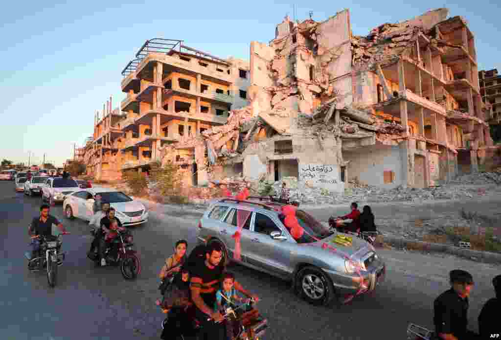 시리아 반군 점령 지역인 아리하 마을에서 부서진 건물 앞으로 결혼 축하행렬이 지나가고 있다.