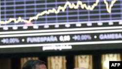 Traders look at a stock index board at Madrid's bourse, January 16, 2012
