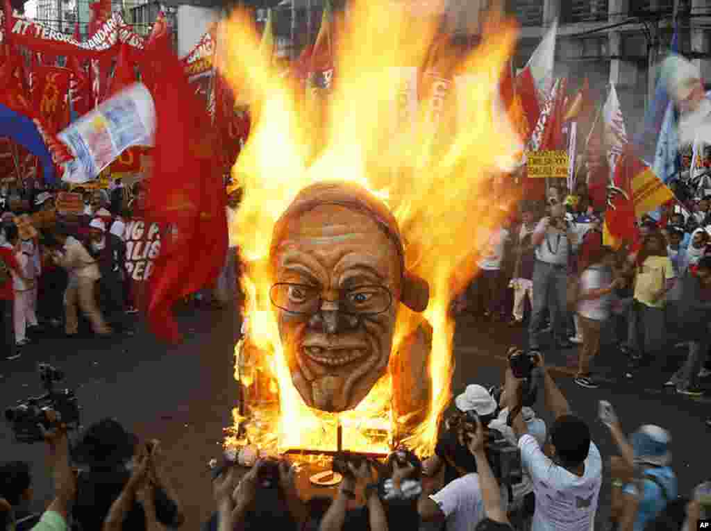 ພວກປະທ້ວງທີ່ຟີລິບປີນ ຈູດຮູບຫຸ່ນຂອງປະທານາທິບໍດີBenigno Aquino III ໃນລະຫວ່າງການໂຮມຊຸມນຸມ ຢູ່ໃກ້ໆທໍານຽບ ປະທານາທິບໍດີ ທີ່ນະຄອນຫລວງມະນີລາ ເພື່ອສະຫລອງວັນກໍາມະກອນ ສາກົນ, ວັນທີ 1 ພຶດສະພາ ຫລື May Day ທີ່ຟີລິບປີນ. (AP Photo)