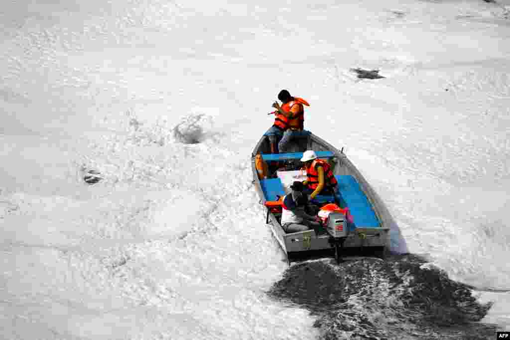 Civic workers spray defoamer on the polluted waters of river Yamuna laden with foam, in New Delhi, India.