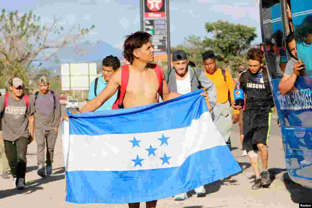 Uno de los integrantes de la caravana de migrantes sostiene una bandera nacional hondureña, en su camino hacia Estados Unidos, en Cucuyagua.