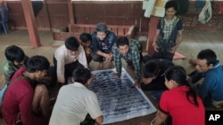 In this March 2020 photo provided by the Southern Youth Development Organization, community members check information in a poster they produced which documents local fish, before publication, in the Lenya area of the Tanintharyi region in southern Myanmar.