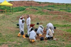 FILE - Workers start the exhumation process of a mass grave in Iraq's northwestern region of Sinjar, March 15, 2019.