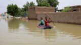 FILE - Young boys navigate a flooded street on a makeshift raft through the town of Salmaniya, about 25 miles (35 km) southwest of the capital, Khartoum, Sudan, Sept. 17, 2020. 